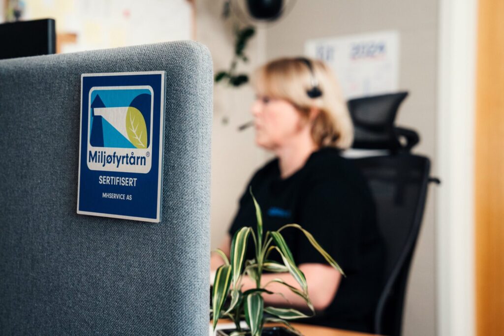 Kjersti Flataker i kundeservice hos MHService, med Miljøfyrtårn-sertifisering i forgrunnen